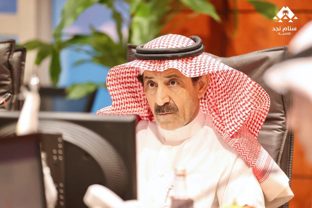 رجل يرتدي ثوبًا سعوديًا تقليديًا وعقالًا، يبدو عميق التفكير أثناء اجتماع.