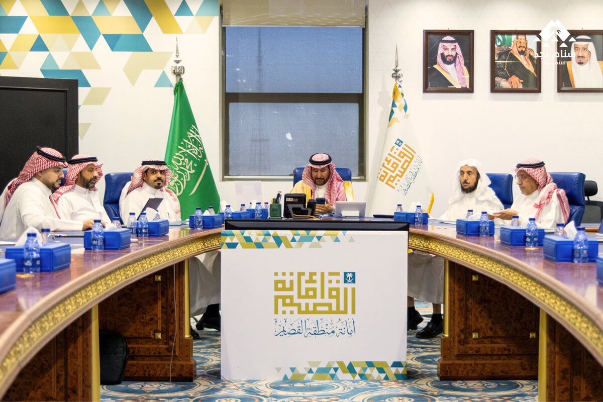 اجتماع رسمي في غرفة مخصصة بمشاركة عدد من الرجال يرتدون الزي التقليدي السعودي، مع لافتة تحمل شعار منظمة فوق الطاولة.